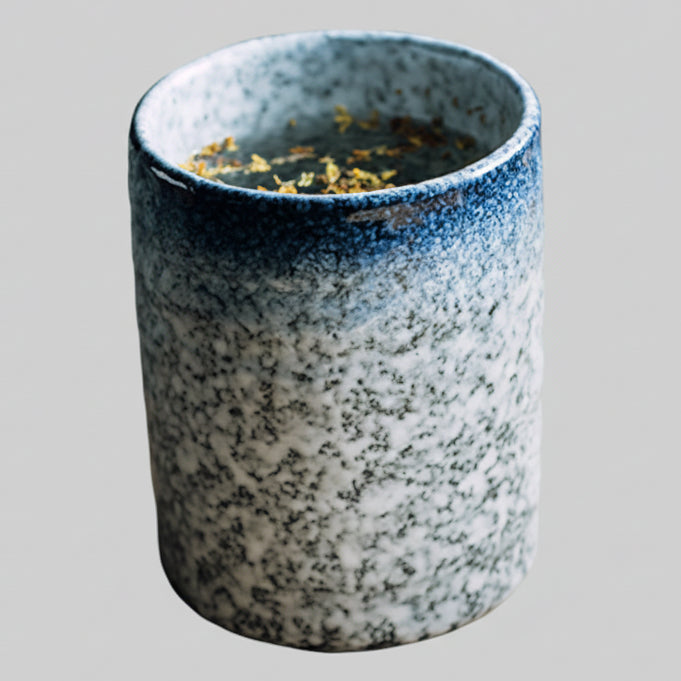 Tasse Yunomi tenue à deux mains, remplie de thé vert